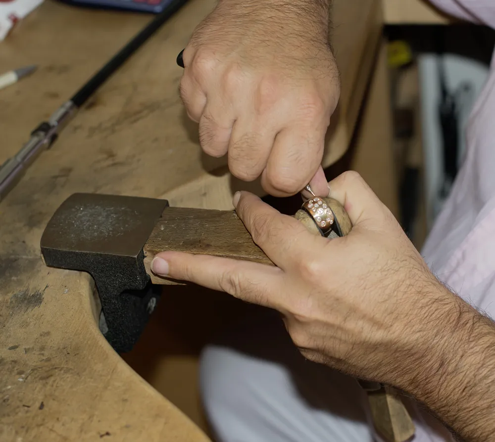 Goldschmied fasst einen Edelstein in einen Ring – Goldschmiede Hannover